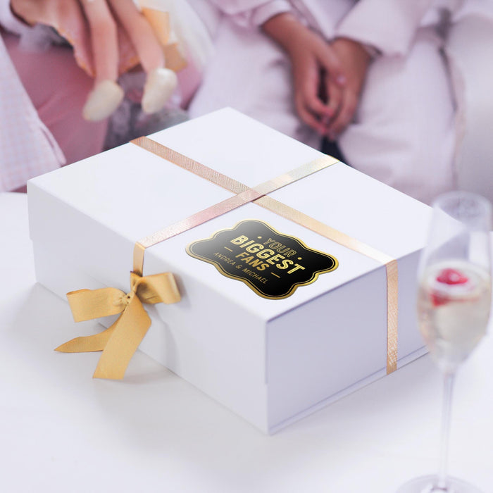 White gift bags with tissue paper decorated using personalized “Your Biggest Fans” holographic foil wedding gift tags. A stylish option for wedding welcome bags, bridal party gifts, and favors.