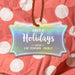 Personalized Happy Holidays slim rectangle hang tag displayed against red and white polka dot holiday wrapping paper.