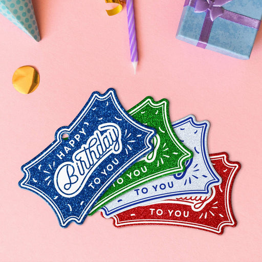 Four birthday tags in glitter red, glitter blue, glitter green, and glitter white.