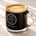 A glass mug filled with a dark liquid, likely coffee, with a foamy top. The mug has an engraved message that reads "Happy Father's Day Love, Daniel".