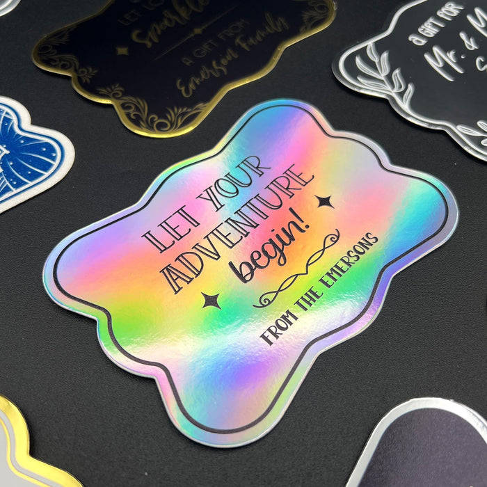 Close-up display of the personalized “Let Your Adventure Begin” wedding gift tag in holographic rainbow foil. The colorful foil finish and custom sender names create a modern and elegant wedding keepsake.