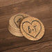 Round cork coasters featuring a large hand-drawn heart outline with personalized initials on a wood table.