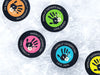 Multiple hockey pucks ontop of ice rink with 1st fathers day handprint designs with different names and colors