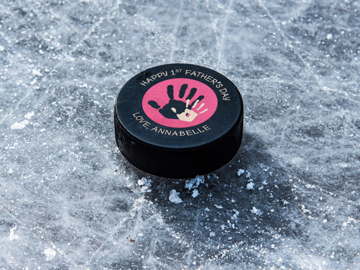 hockey puck ontop of ice with pink 1st Fathers Day handprint design with the name Annabelle printed on it