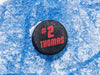 single hockey puck on ice rink with name and number design printed in red that says Thomas number 2