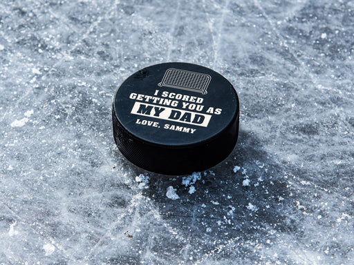 hockey puck on top of ice with white I scored you as my dad design with the name Sammy printed on it