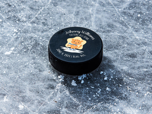 hockey puck ontop of ice with blue future all star cartoon tiger design with the name Johnny Williams on it with birthday and weight