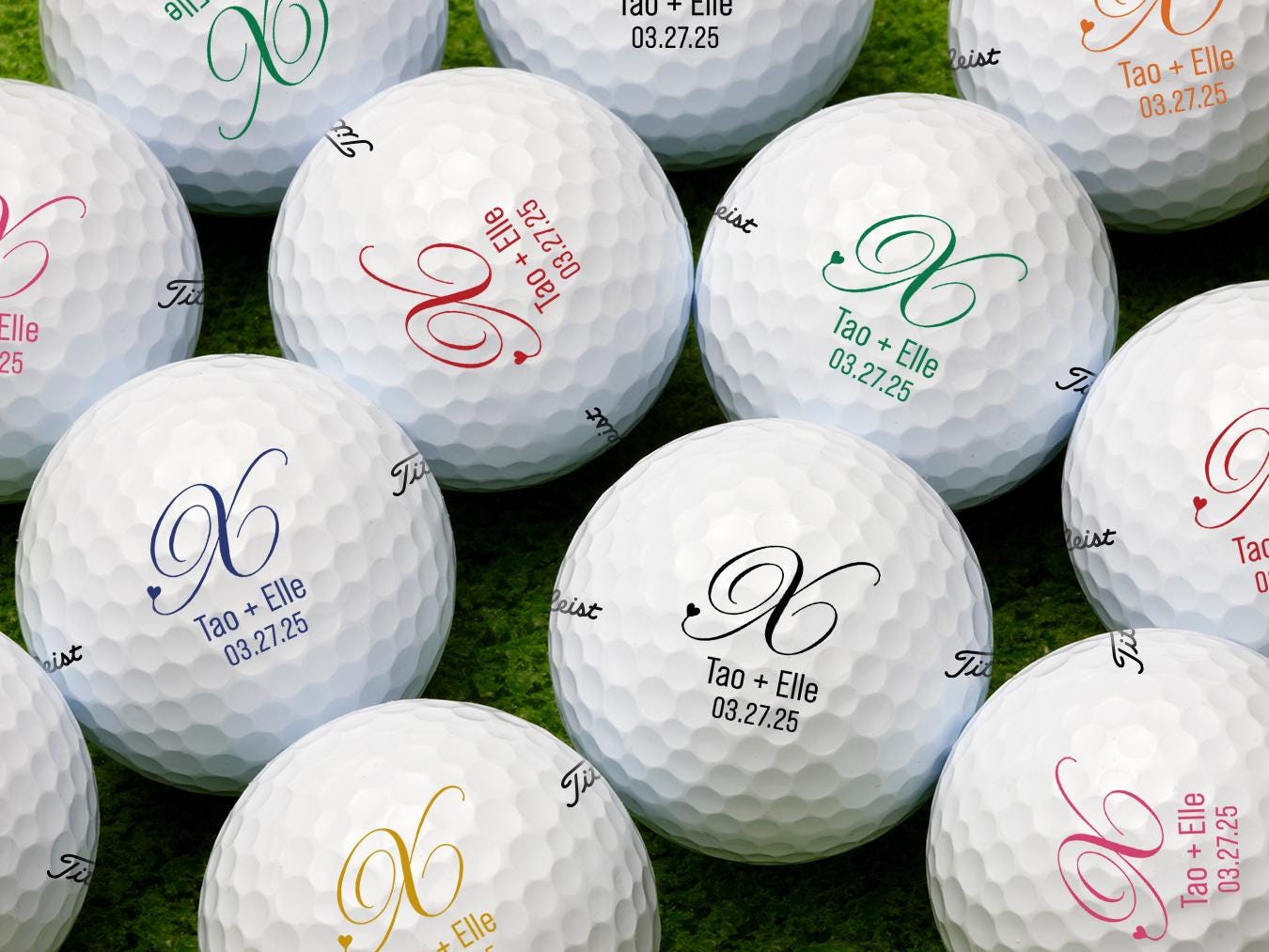 Single white Titleist golf ball with Heart Initial Monogram design on white golf tee with golf course grass in the background