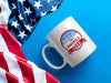 white mug on white background that has red white and blue patriotic American design with stars with Typography that says "Bartlet for America 2024" on blue background next to the American flag