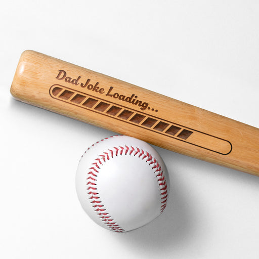 Photo of laser engraved Dad Joke Loading mini bat design next to a baseball