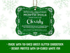 A green glitter hanging cardstock Santa gift tag is shown on a white background with green snowflakes. Text underneath the tag reads: Made with no-shed green glitter cardstock, Design printed with UV-cured white ink.
