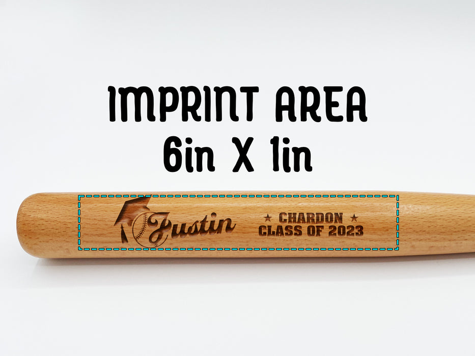 wooden mini baseball bat with custom laser engraved design that features a name with a graduate cap and says "Justin, Chardon, Class of 2023" on a white surface with the words imprint area on it