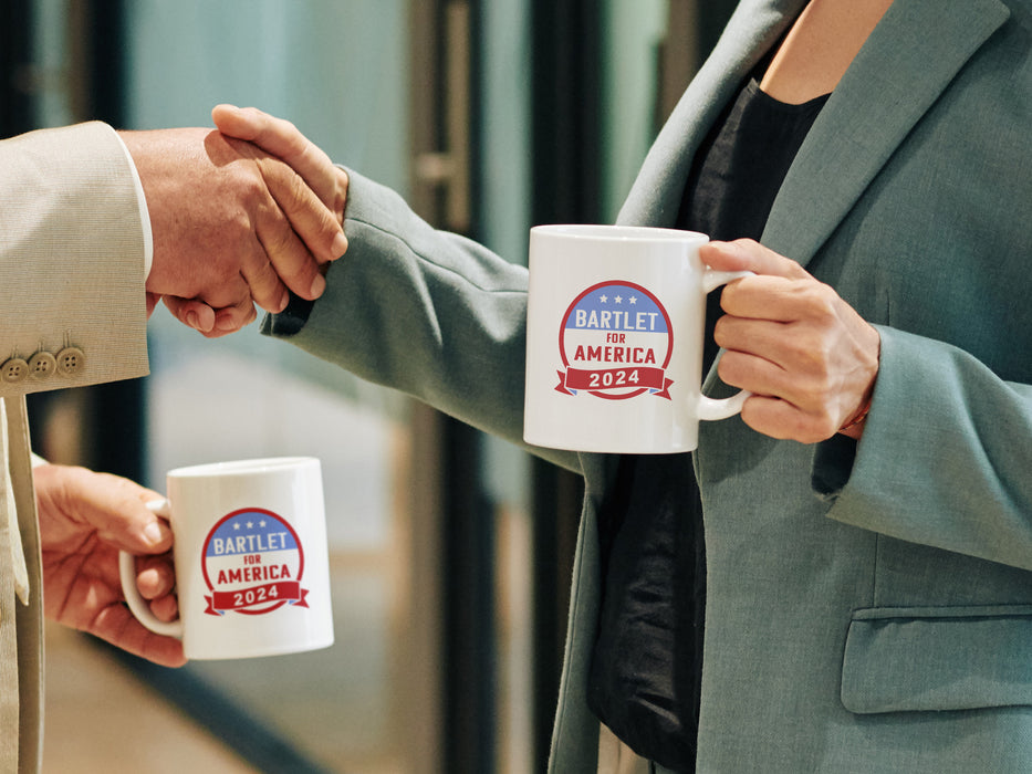 two business people shaking hands both holding white mugs with red white and blue patriotic American design with typography that says "Bartlet for America 2024"