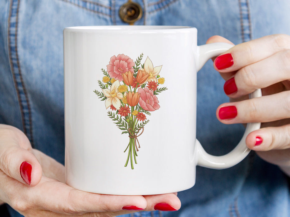 woman's hands with red painted nail polish holding a 15 ounce ceramic mug featuring artwork of a bouquet of pastel spring flowers