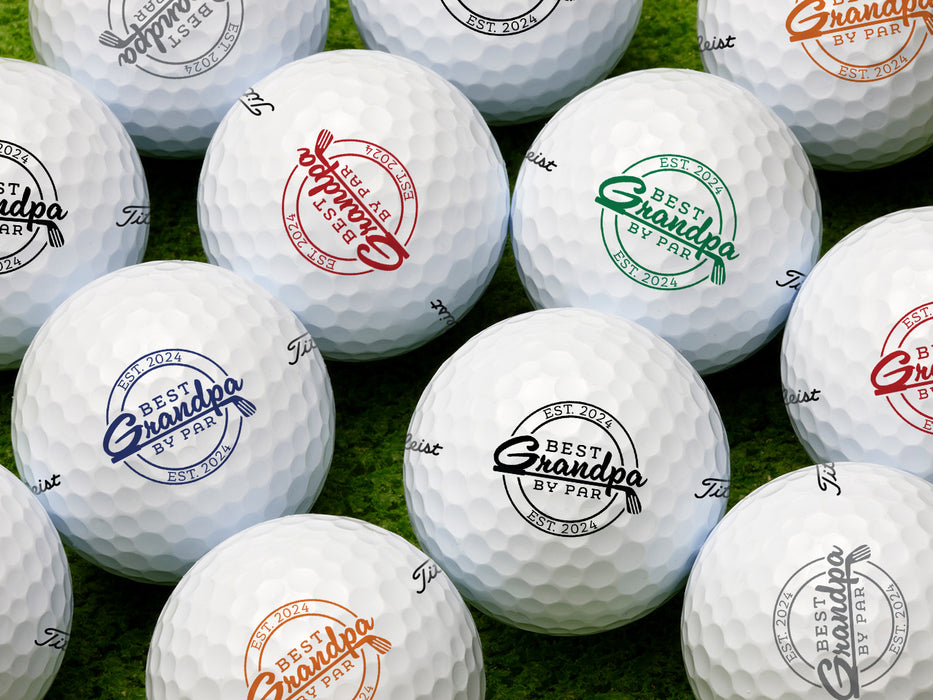 Multiple white titleist golf balls with Best Grandpa By Par design in all available color options on golf course grass