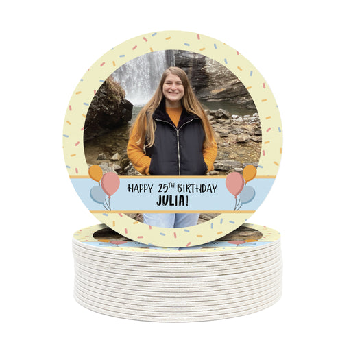 A single coaster is shown on top of a stack of other coasters. Coasters are designed with multi-colored confetti, yellow, blue, and a custom photo. Coaster text reads Happy 25th birthday Julia!