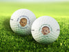 Two white Titleist golf balls with first Father's Day baby photo designs on top of golf course grass background