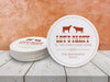 A stack of coasters by a single coaster on wooden table. Coasters feature Til The Cows Come Home design. Design shows two cows with the saying Lets Party Til The Cows Come Home with newlyweds last name and wedding date.