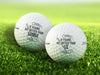 Two white Titleist golf balls with If Found, Hit Better Than designs with different names on top of golf course grass