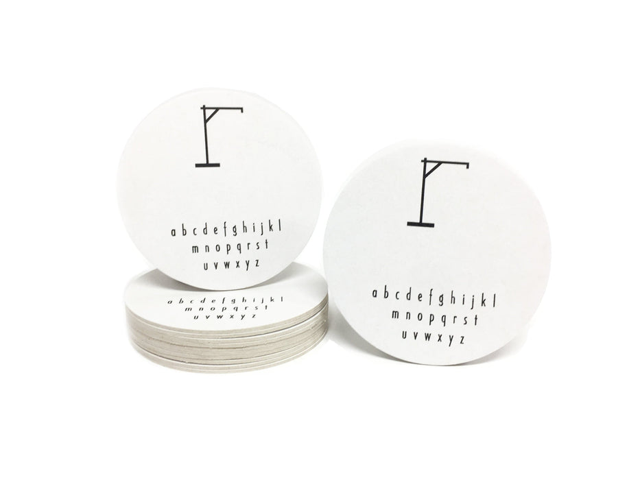 Single coaster is shown on top of a stack of coasters with another coaster sitting next to it on a white background. Coasters feature Hangman Game design. This design has a hangman game printed in black on white coasters.