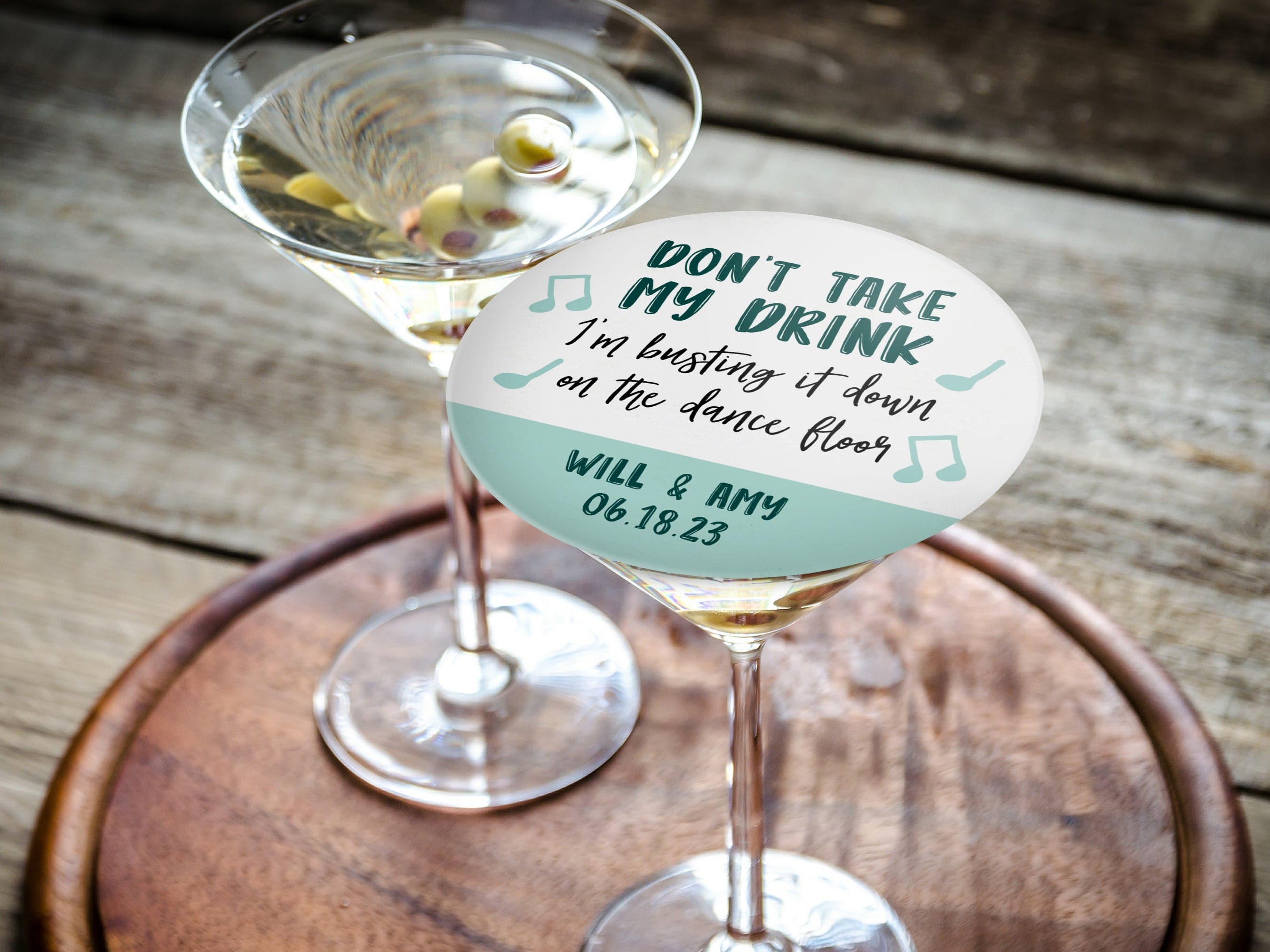 Single coaster is shown on top of a stack of coasters. Coasters say Don't take my drink, I'm busting it down on the dance floor. Married couple names are below with wedding date.