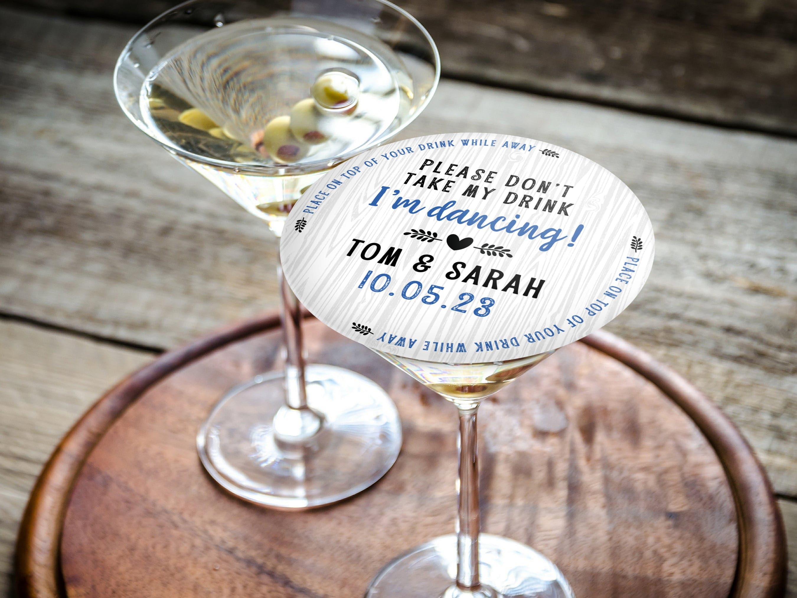 Single coaster is shown on top of a stack of coasters. Coasters say Please Don't Take My Drink I'm Dancing with wedding couple names and wedding date. The words, place on top of your drink while away, act as a border around coaster.