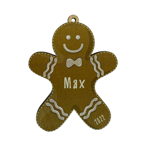 Ornament shown with Gingerbread Boy design. The ornament is wooden and shaped like a gingerbread boy. Name and year are written on ornament in white.