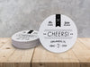 A stack of coasters by a single coaster on wooden table. Coasters feature CHEERS! Modern Wedding design. Coasters show married couple names and first name initials, the word “CHEERS!”, and the wedding location and date. Design is printed in black on a white coaster. These coasters also have decorative keys, lines, and dots on it.