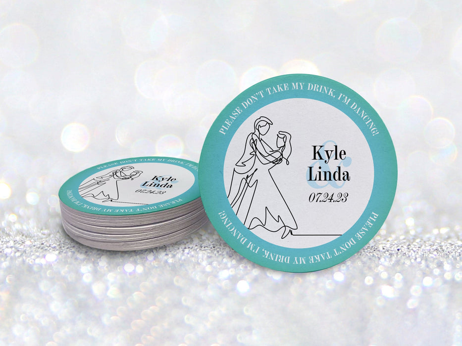 A stack of coasters by a single coaster in front of a glittery background. Coasters say Please Don't Take My Drink, I'm Dancing in white around a teal border with an illustration of a married couple dancing beside their names and wedding date.
