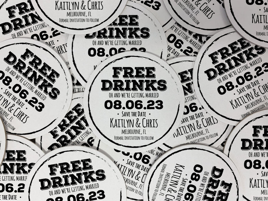 Multiple coasters spread in all different directions. Coasters feature Free Drinks Save the Date design. Design has a circular brushstroke around the text “Free Drinks, Oh And We’re Getting Married, 08.06.23, Save The Date, Kaitlyn & Chris, Melbourne, FL, Formal Invitation to Follow”. Design is printed in black on a white round coaster.