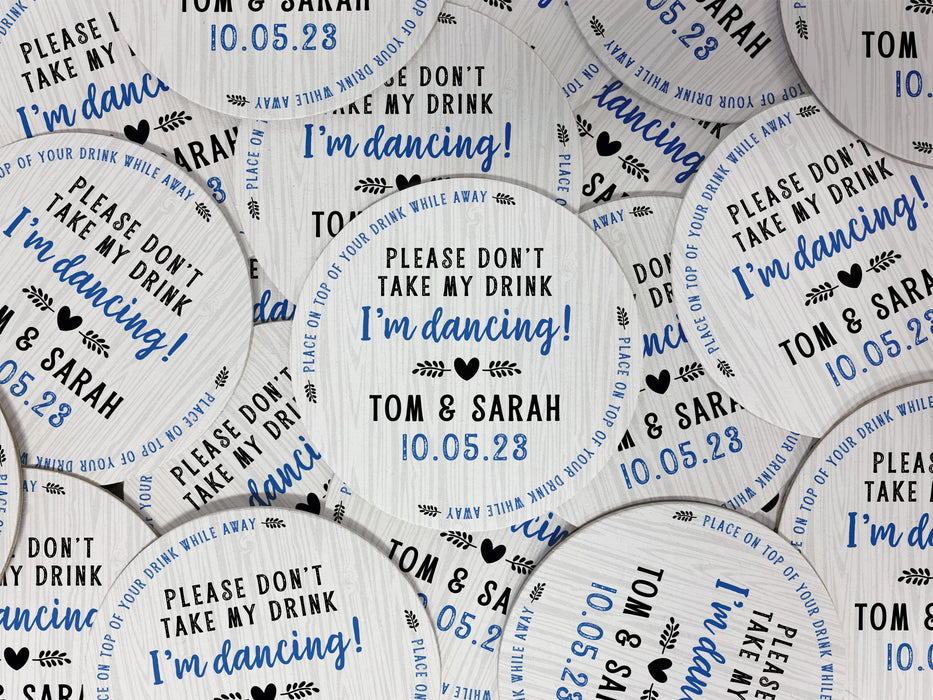 Multiple coasters spread in all different directions. Coasters say Please Don't Take My Drink I'm Dancing with wedding couple names and wedding date. The words, place on top of your drink while away, act as a border around coaster.