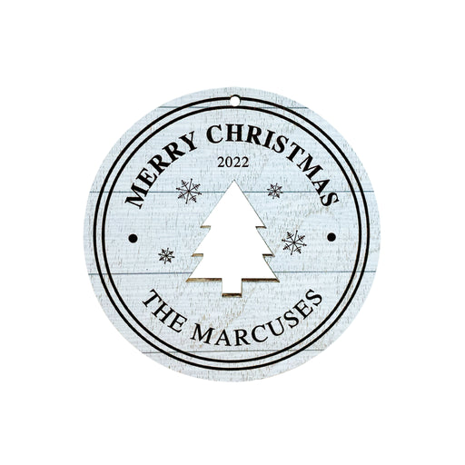 Ornament shown features Rustic Tree design. The ornament is wooden and shaped like a circle with a Christmas Tree cutout in the middle. Ornament says Merry Christmas, Year, and Family Name