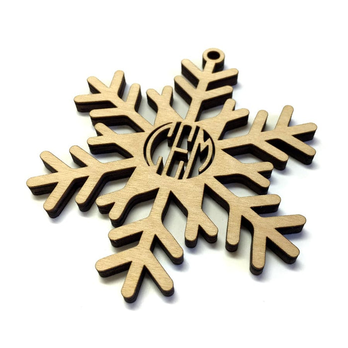 Ornament shown on white background. Snowflake Monogram ornament design is featured. The letters CEM can be seen as a monogram in the center of ornament. Ornament is made of birch wood and laser cut.