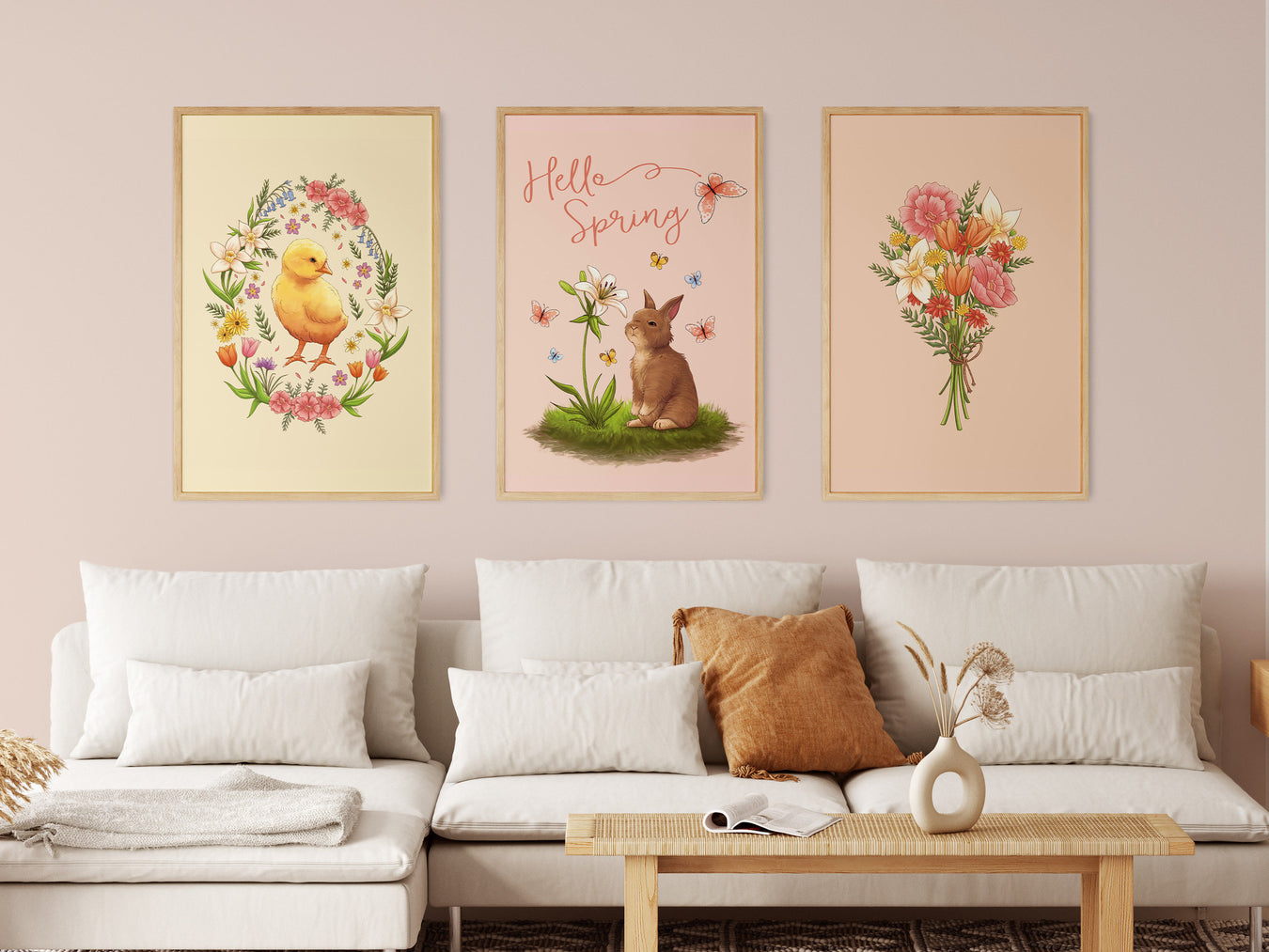 three easter prints with pastel easter artwork in wooden frames on white living room wall surrounded by household furniture such as a white couch, throw pillows, coffee table, etc