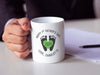 man in business suit holding a a white ceramic mug that says happy first fathers day love Charlotte with a footprint design with a green heart with the year 2024 in it next to papers and a pen