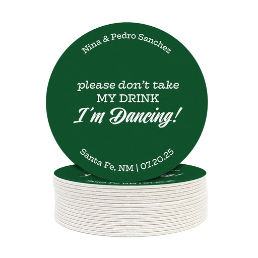 A stack of custom round coasters against a white background. Coasters say Please don't take my drink, I'm dancing with wedding couple's names, location, and wedding date.
