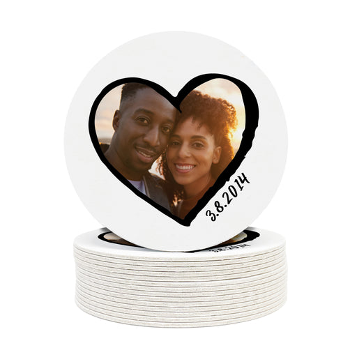 A couple in a heart - shaped photo on a stack of white coasters.