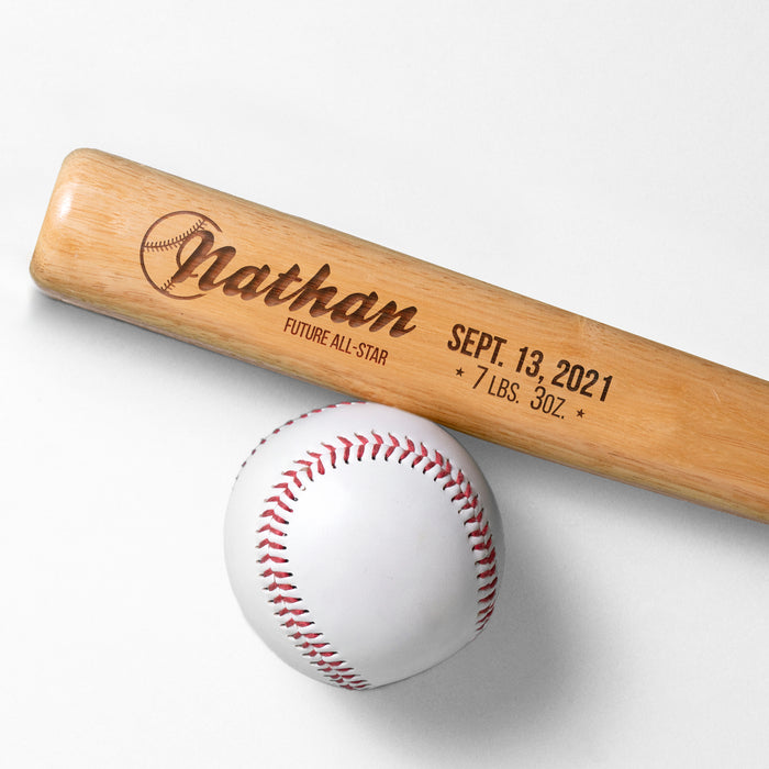 wooden mini baseball bat with custom laser engraved design that features a baby name design with a date and info text and says "Nathan, Future All-Star, Sept. 13, 2021, 7 LBS. 3oz" on a white surface next to a base ball