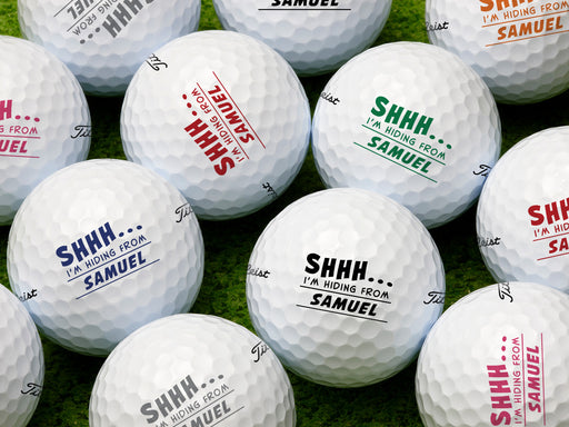 Multiple white Titleist golf balls with Shhh I'm Hiding From design in all available color options on golf course grass
