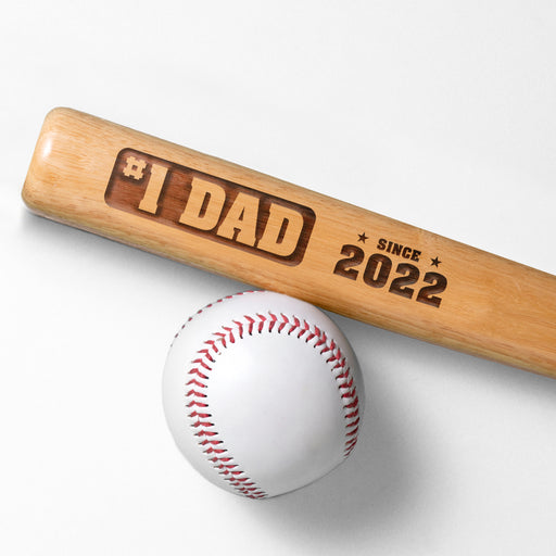 Photo of laser engraved #1 Dad mini bat design next to a baseball