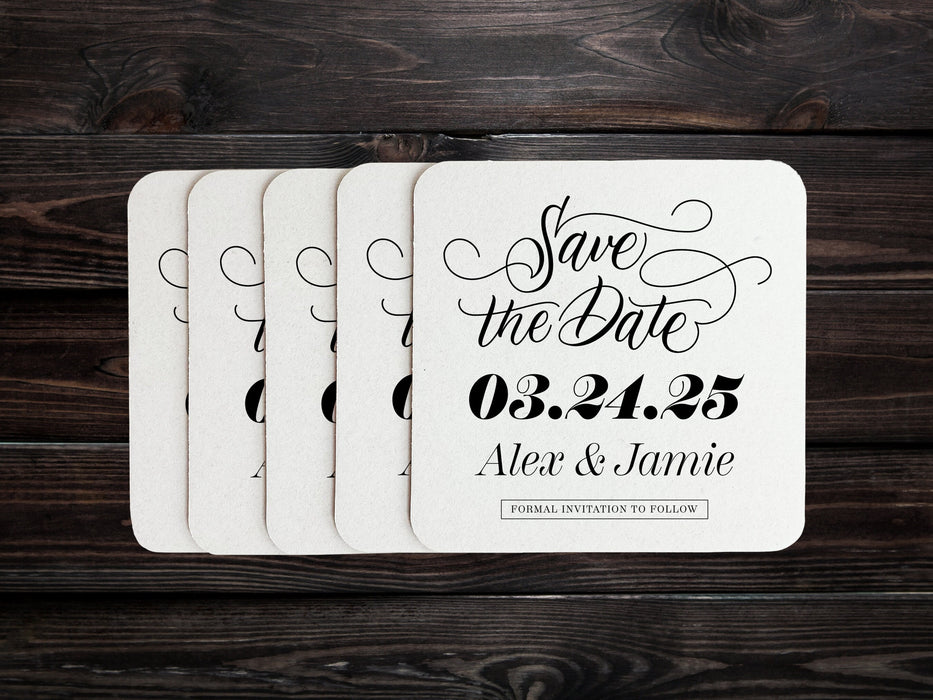 Stack of coasters spread out on dark wood table. Coasters say Save the Date, wedding date, married couple names, and formal invitation to follow.