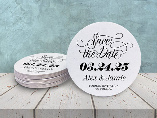 A stack of coasters by a single coaster on wooden table. Coasters say Save the Date, wedding date, married couple names, and formal invitation to follow.