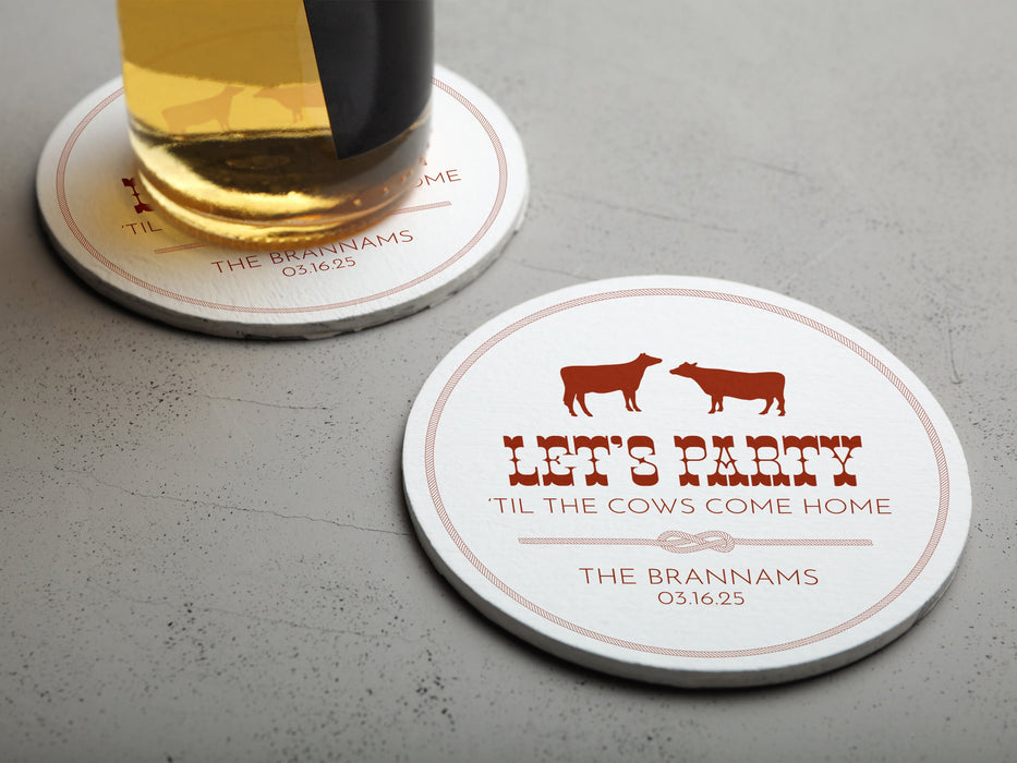 One coaster has a beer glass on it and an empty coaster sits beside it. Coasters feature Til The Cows Come Home design. Design shows two cows with the saying Lets Party Til The Cows Come Home with newlyweds last name and wedding date.