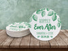Stack of coasters beside a single one is shown on a wooden table against a green wall. Coasters feature Hoppily Ever After design. This design uses green lettering and sketched drawings of beer hops. Wedding couples names and date can be customized.