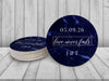 A stack of coasters by a single coaster are shown on a white wooden background.Coasters feature Love Never Fails design. This design has a dark blue marble background and the happy couples first name initials and wedding date in white writing.