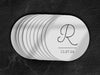 A stack of coasters are spread out on a dark black marble surface. Coasters feature Monogrammed Initial design. This design can be customized with a large initial and date in black writing on a plain, white background.
