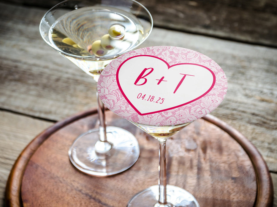 One coaster is being used as drink cover on top of a martini glass. Coasters feature Heart and Lace design. These are designed with the bride and groom first name initials and wedding date surrounded by a hot pink heart outline and light pink lace.