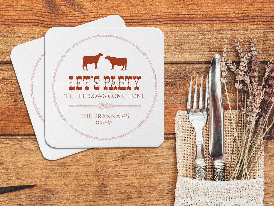 Two coasters are shown stacked on top of each other on a wooden table. Coasters feature Til The Cows Come Home design. Design shows two cows with the saying Lets Party Til The Cows Come Home with newlyweds last name and wedding date.