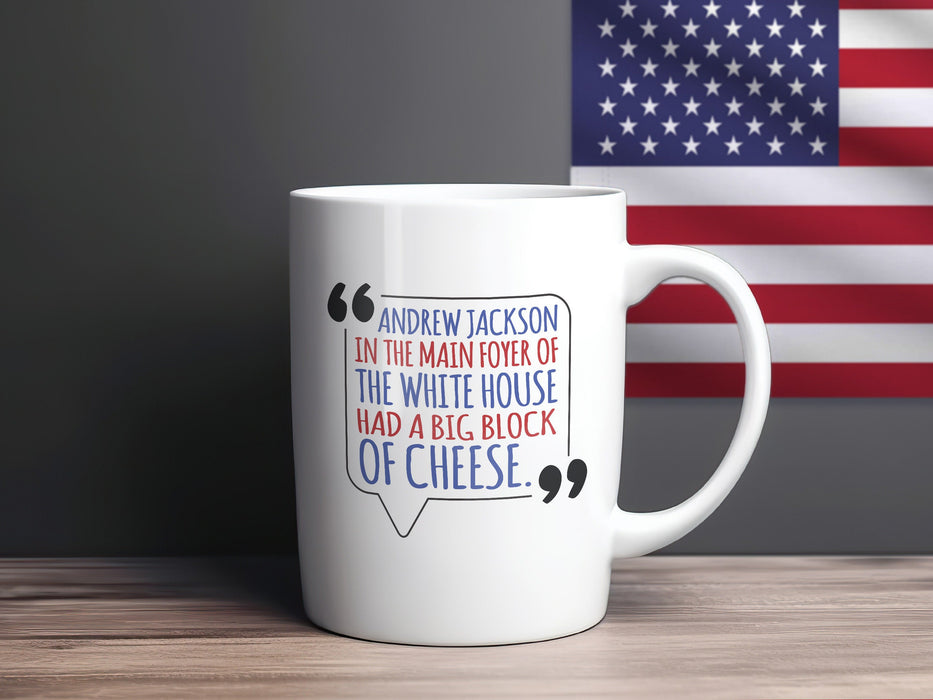 white mug on wooden table in front of American flag banner with an American west wing design and Typography that says Andrew Jackson in the Main Foyer of The White House had a Big Block of Cheese.