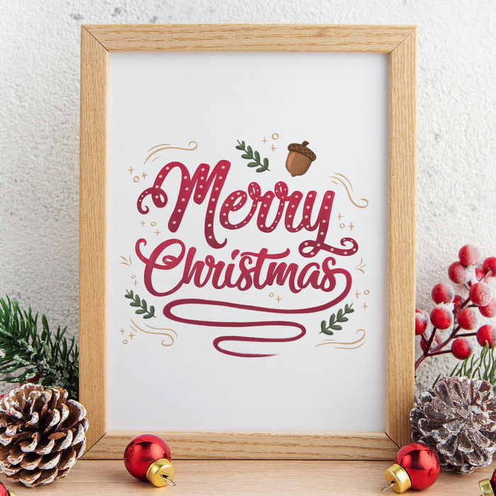 wooden frame with Merry Christmas typography print ontop of wooden countertop surrounded by winter decor such as pinecones, pine leaves, holly berries, and red ornaments